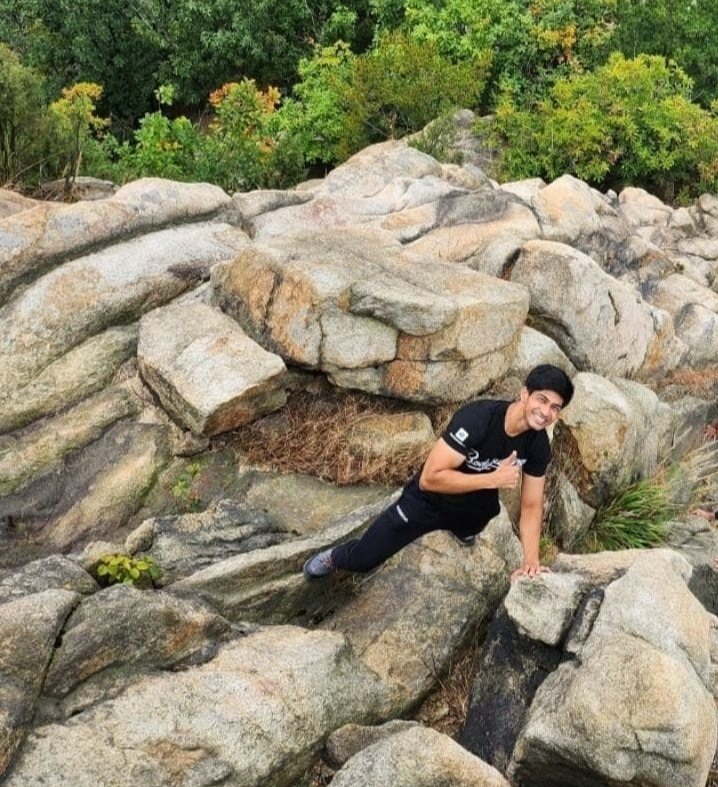 Ayush Patel hiking over granite boulders on a mountain in Korea